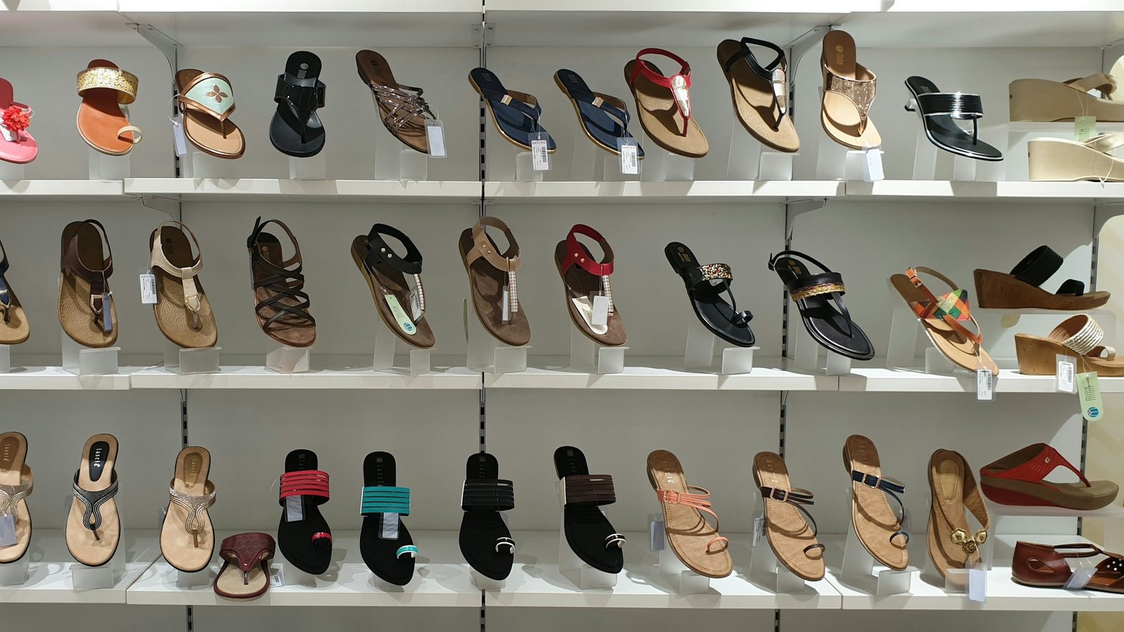 A wall of sandals, flip flops and wedges on display in a footwear store